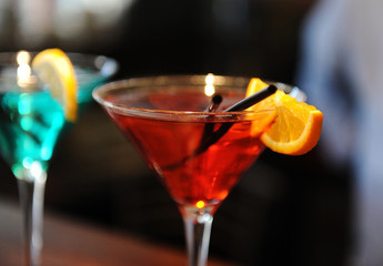 Red cocktail on the bar. Decorated with a lemon slice. Close up.