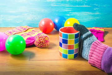 Focus Spot women's hands, gloves, Silk hat, colored balls and a cup of coffee on wood table. In the winter. Warm up with hot coffee, sunlight helps the body to warm up.