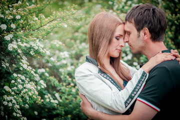 Fototapeta premium Dating. Young woman and man walking, couple in love relaxing in blossoming trees park at sunny spring day