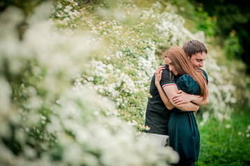 Dating. Young woman and man walking, couple in love relaxing in blossoming trees park at sunny spring day