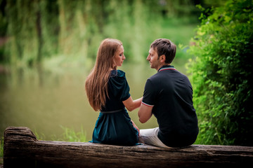 Romance and love. Dating and park. Loving couple sitting together on grass near the lake.