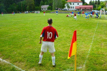 Football player on green pitch during sunday local match.
