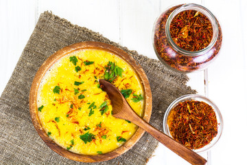 Pumpkin cream soup with saffron and parsley in a wooden bowl