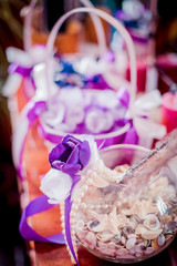 Wedding accessories in violet colors on the table. Ring candle shoes at wooden background