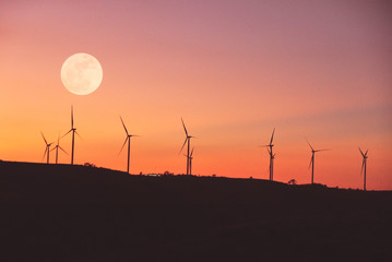 Obraz premium Landscape of turbine electric on hill with silhouette sky and full moon