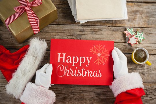 Composite image of santa claus holding a red placard