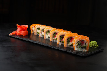 Salmon Sushi Roll with avocado, tofu, tobiko on a blackboard.