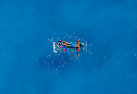 The Boy In The Water In The Swimming Pool Or The Sea On A Mattress In The Summer Vacation. View From Above.