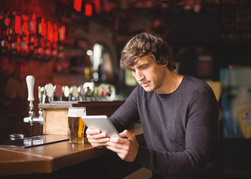 Man using digital tablet at bar counter