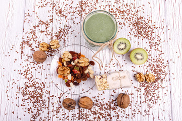Fototapeta na wymiar healthy green smoothie with walnut,candied fruit and kiwi lie on