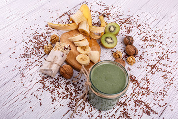 healthy green smoothie with walnut and fruits lie on the table