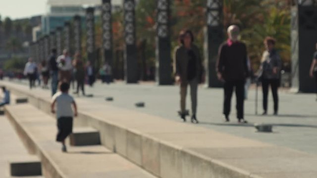 Unfocused background video of unrecognizable people walking in sunny weekend day on crowded pedestrian street