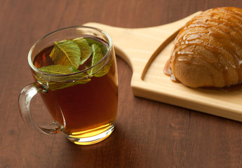 bread on a wooden plate and a glass of tea