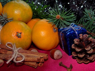 новогодние мандарины лежат на красном фоне с веточками ели  и шишкой       