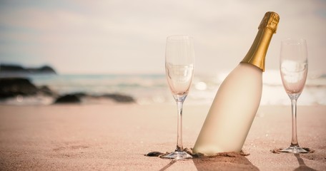 Fototapeta premium Butelka szampana i dwie szklanki na piasku