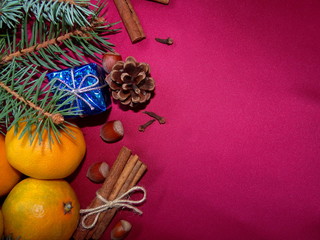 новогодние мандарины лежат на красном фоне с веточками ели  и шишкой       