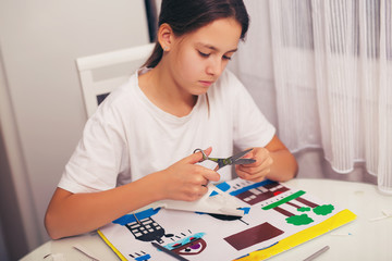 Beautiful girl cutting paper on the art lesson class. Children education concept