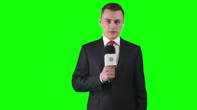 Lockdown of man in formal suit standing against green screen background gesticulating and talking passionately into microphone