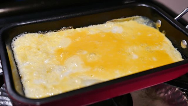 Frying delicious egg omelette at home with a pan
