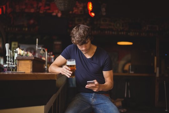 Man using mobile phone while having glass of beer