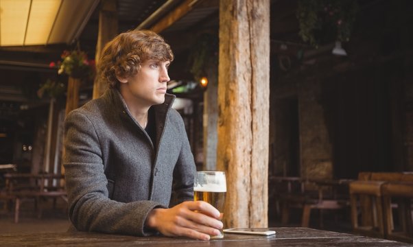 Man sitting in bar with glass of beer on table