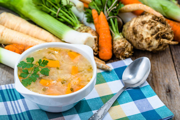 Vegetable soup in a bowl and fresh vegetables on wooden table