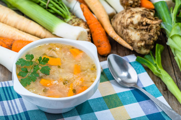 Vegetable soup in a bowl and fresh vegetables on wooden table