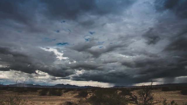 Time Lapse 2060: Time lapse storm clouds and lightning over a desert plain.