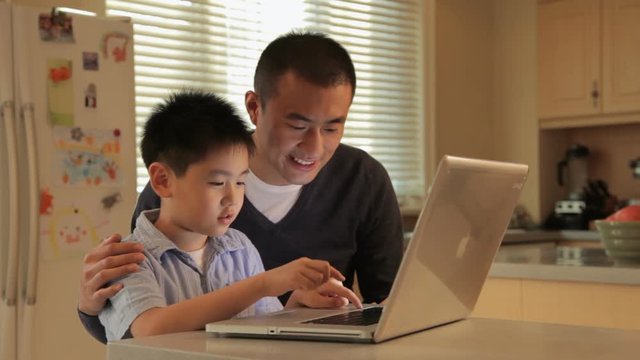 MS Father and son using laptop on kitchen counter / China
