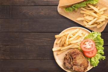 Grilled pork chop steak and hot dogs set on the wooden background.