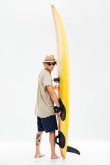 Young surfer holding surfboard and looking over his shoulder