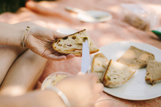 A woman buttering a slice of bread during a pic nic.