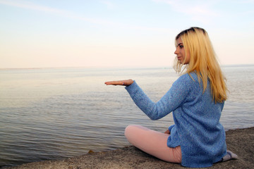 Young girl sitting on the beach with an open hand