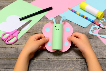 Small child holding paper butterfly in his hands. Child shows paper crafts. Funny butterfly made of...