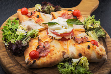 italian pizza calzone with tomato, salad and mozzarella