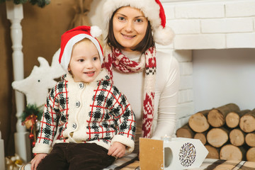 Happy mother and child boy in santa helper hats with gift box.