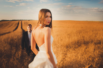 Fototapeta na wymiar beautiful and young bride and groom standing in a field