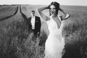 Fototapeta na wymiar beautiful and young bride and groom standing in a field