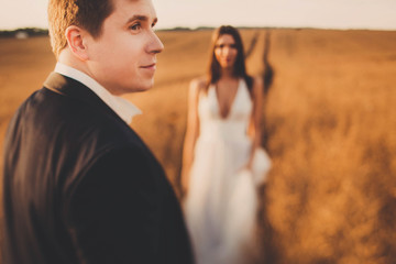 beautiful and young bride and groom standing in a field