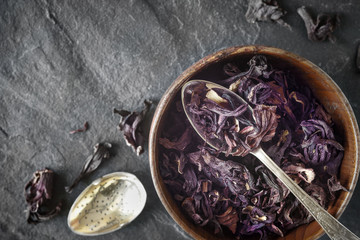 Hibiscus tea in the wooden bowl on the dark stone background top view