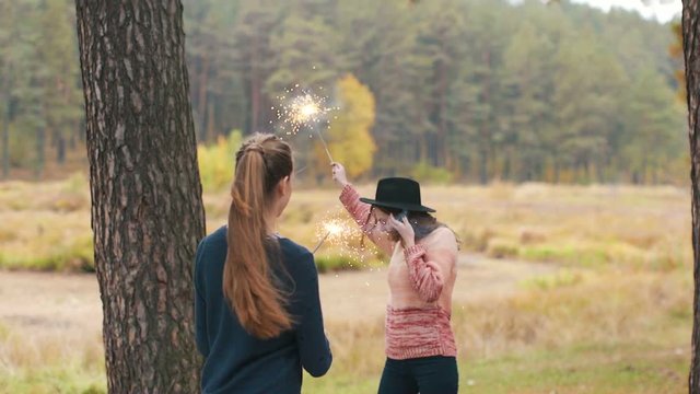 Teenage girls with sparklers celebrate and laugh. Close portrait. Autumn outdoor