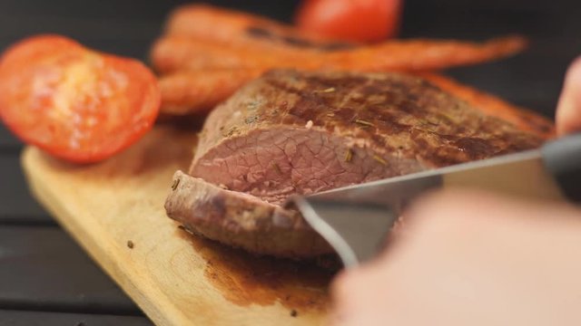 Woman hand cut roasted beef steak
