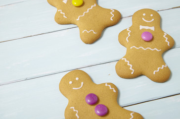Hand decorated gingerbread men on a painted wooden table background with blank space at side