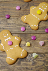 Hand decorated gingerbread men and candy on a rustic wooden table top background