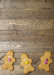 Hand decorated gingerbread men on a rustic wooden table top background with blank space above