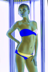 Slim woman in solarium getting sun tan