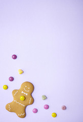 Hand decorated gingerbread men on a pastel purple background with sweets and blank space above