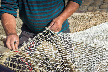 Hands of commercial fisherman mending nets