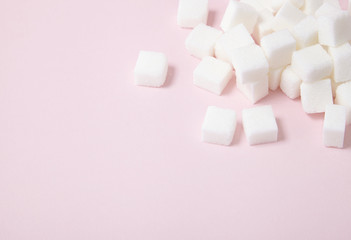 White sugar cubes arranged on a pastel pink background with empty space below - obrazy, fototapety, plakaty
