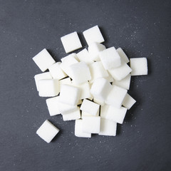 A pile of white sugar cubes on a rustic slate background